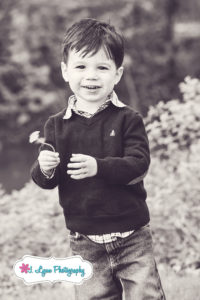 boy holding dandelion with big smile