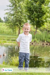 boy standing by pond near ducks