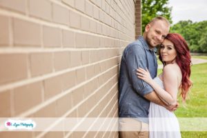 engaged couple against wall